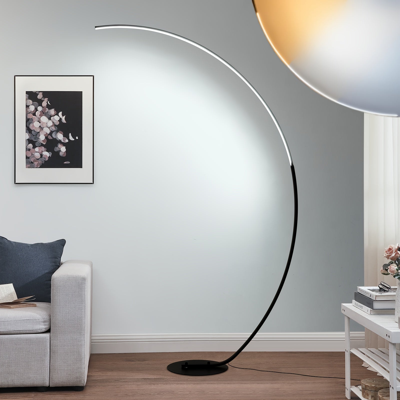 Stylish arc floor lamp casting bright, cool illumination across a contemporary interior space with a sofa and artwork