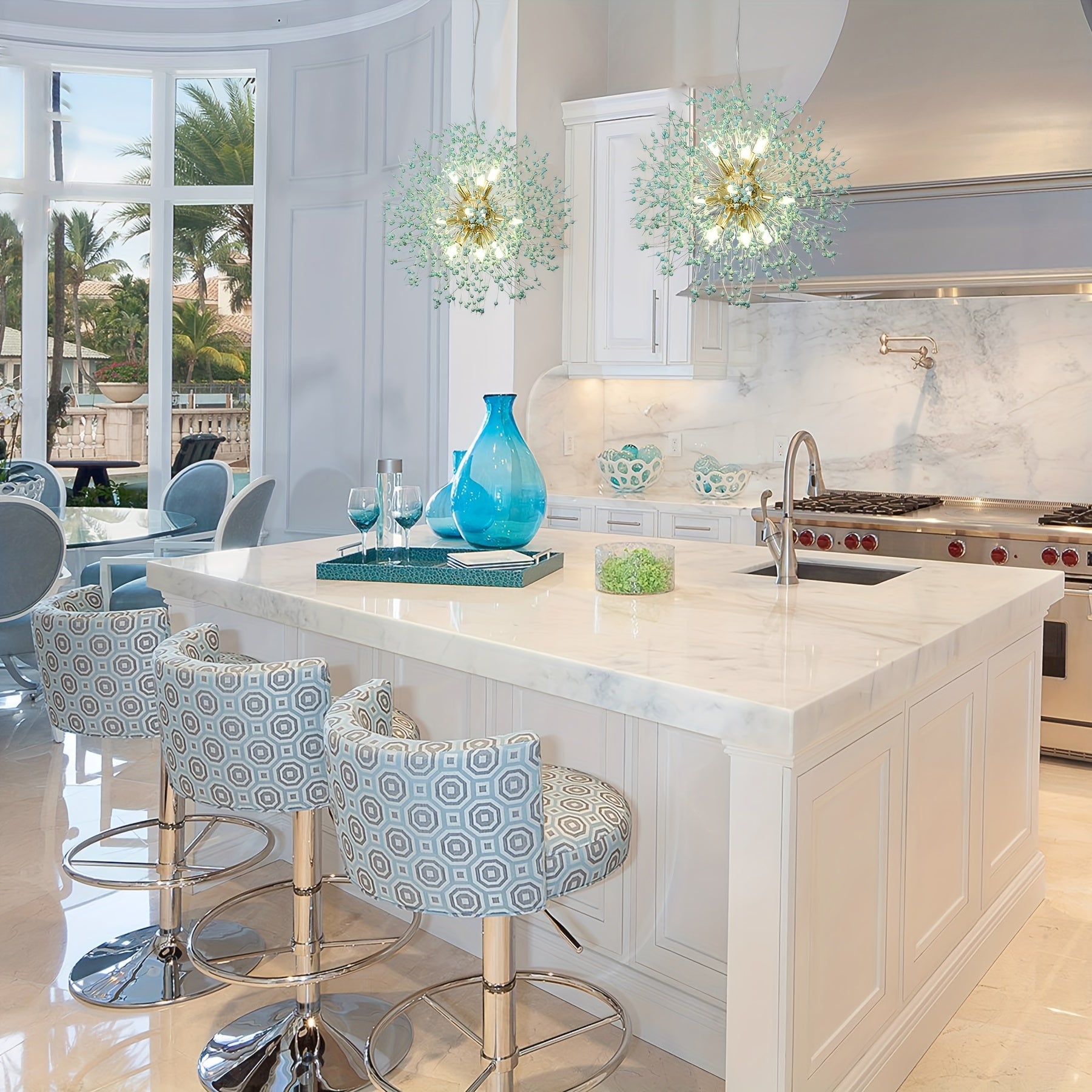 Two dandelion-style chandeliers with gold and green floral accents hanging above a white kitchen island with patterned swivel stools