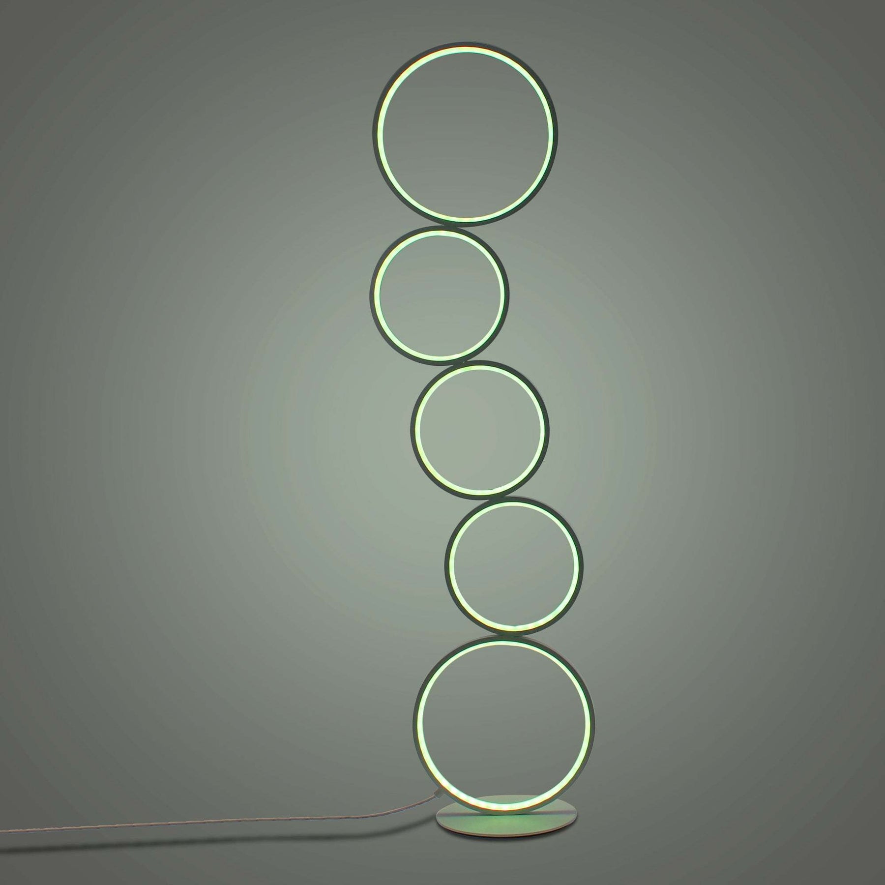Minimalist space showcasing a circular floor lamp with five green glowing rings