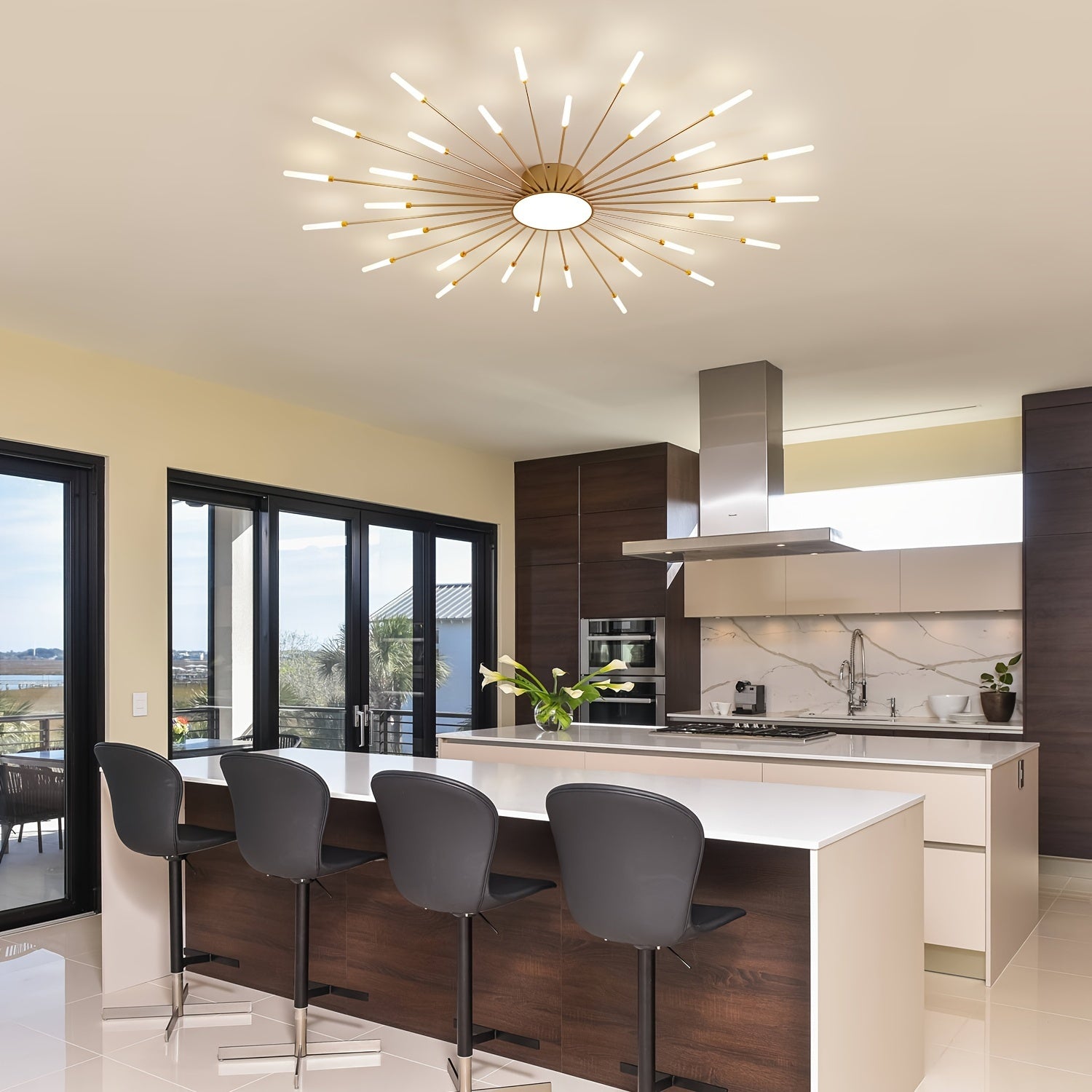 Bright dining and kitchen space with a gold sputnik ceiling light for bedroom installed above the island, surrounded by bar stools and glass doors