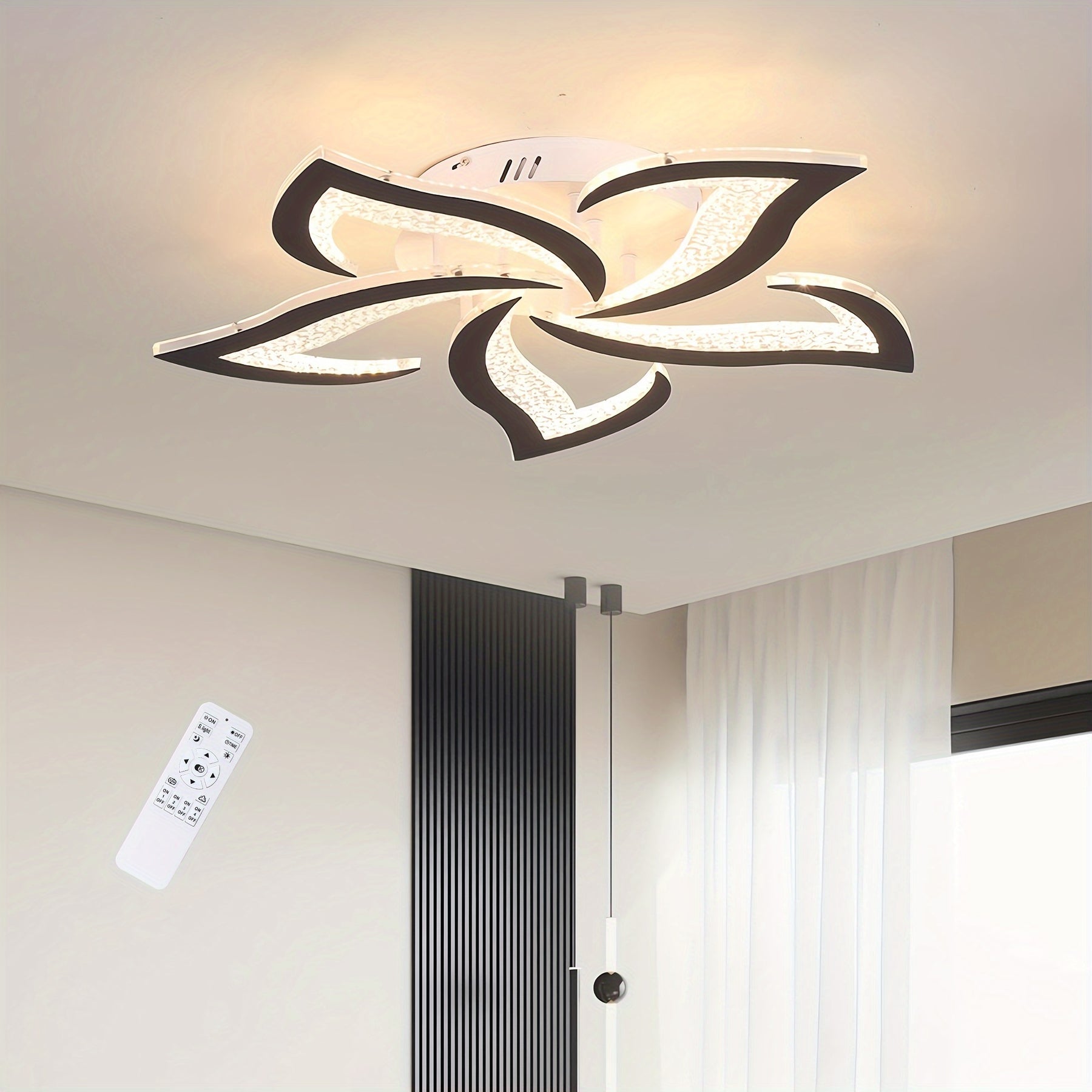 Black-trimmed flower-shaped LED ceiling light illuminating a minimalist space with white curtains and a vertical black wall feature