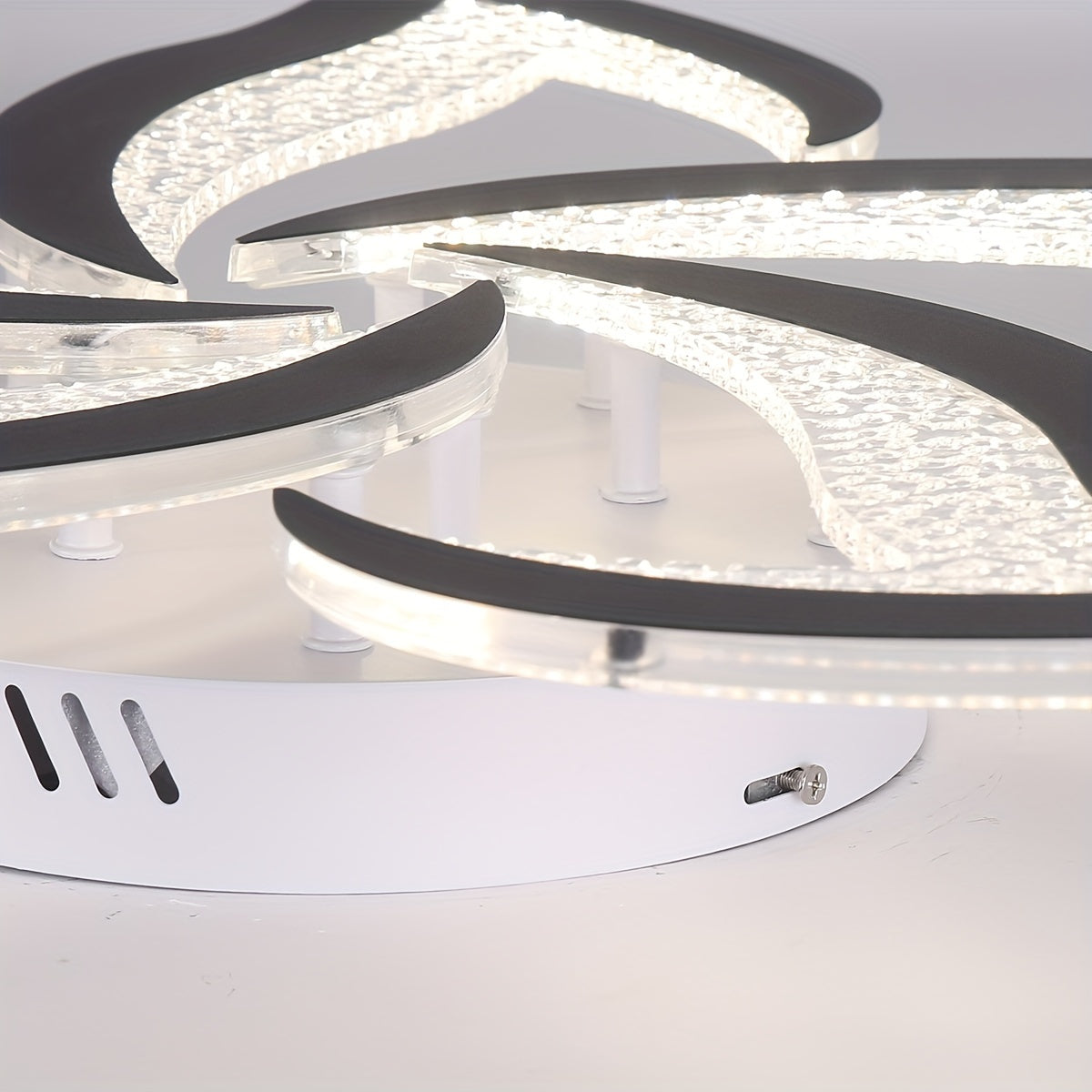 Layered petal-shaped LED panels with clear acrylic and black trim mounted on a white metal ceiling base, highlighting the structural build