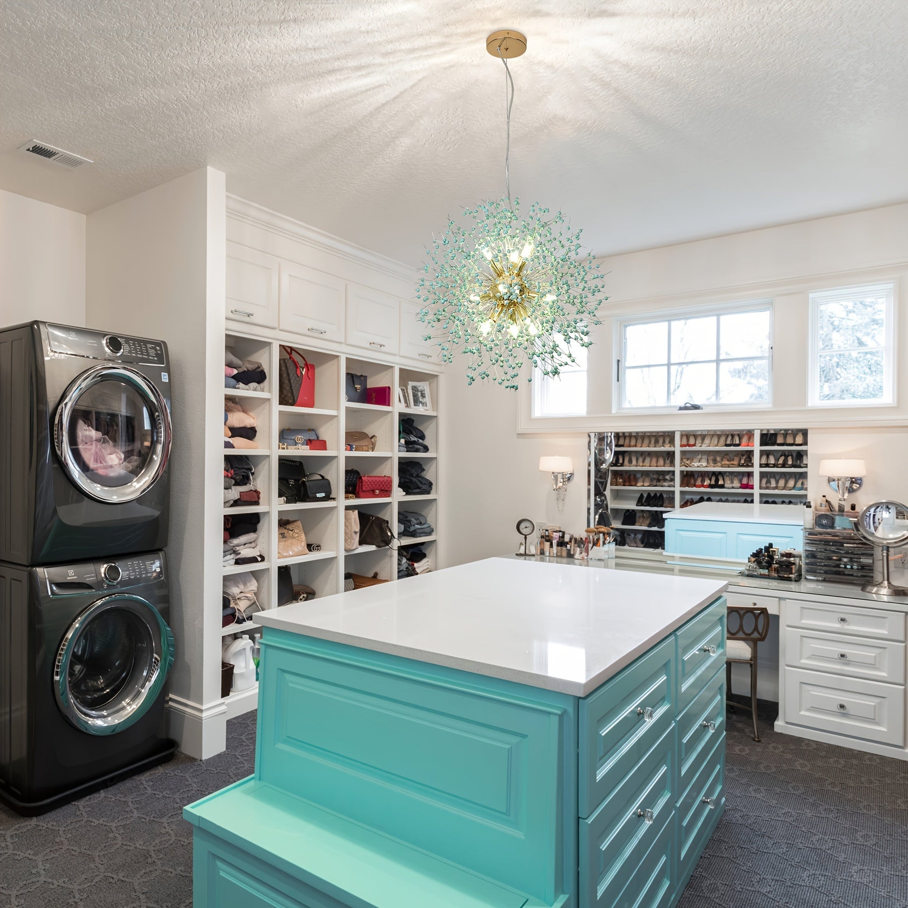 Elegant dandelion chandelier suspended above turquoise island drawers in a modern walk-in closet with open shelving