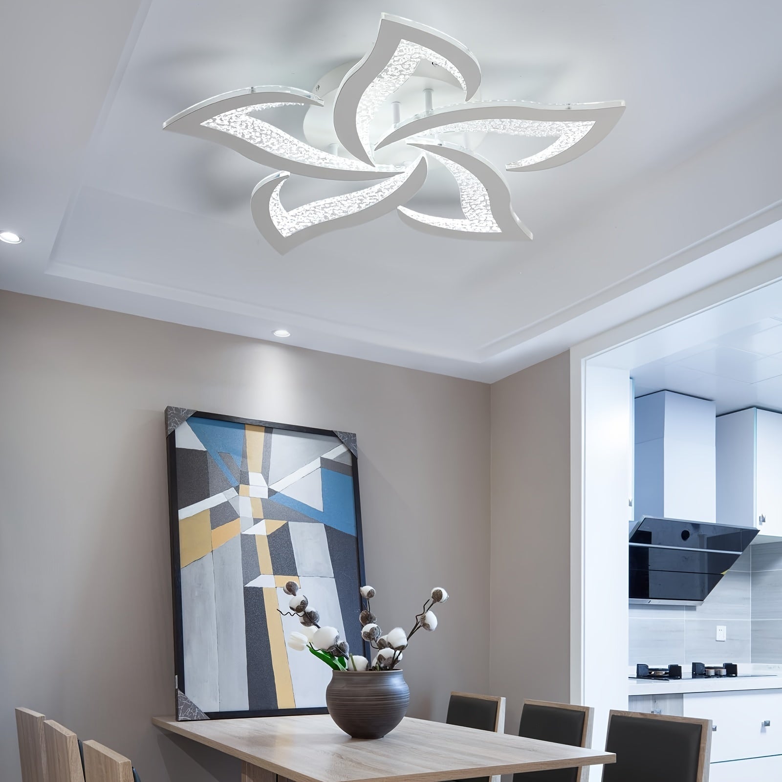 Elegant white LED ceiling fixture with petal-inspired design, installed above a modern dining table beside a geometric wall painting
