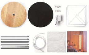 Various components of a modern floor lamp laid out for assembly, including its base, frame, and electrical parts