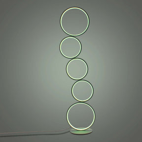Minimalist space showcasing a circular floor lamp with five green glowing rings