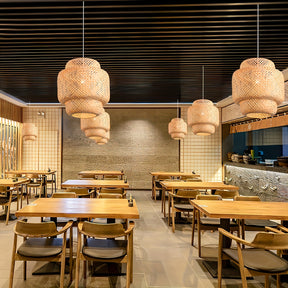 Wooden dining tables arranged in a cozy space with hanging natural lamps, finished with a touch of rattan ceiling light fixture