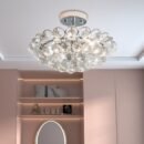 Elegant bubble-style ceiling light with clustered crystal glass droplets, mounted in a soft pink vanity space with backlit shelving