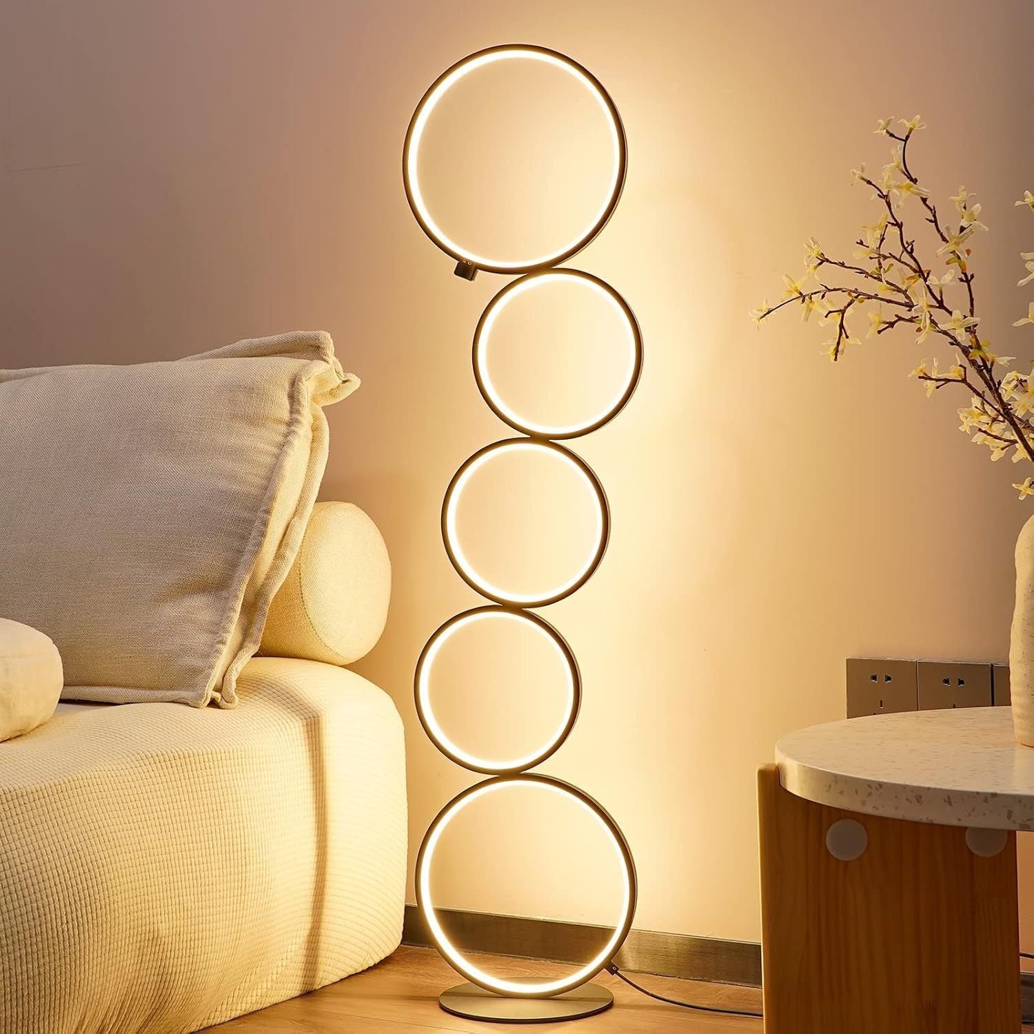 Warmly lit seating area featuring a circular floor lamp with five stacked glowing rings, adding a modern lighting