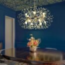 Crystal starburst light fixture hanging above a dark wood dining table in a blue-walled room with a patterned ceiling
